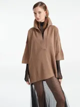 Poncho tejido de punto en color marrón, con escote en V y cuello tipo polo. Presenta un diseño holgado con mangas tres cuartos.