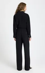 Pantalon sastrero negro de corte recto y tiro alto. Presenta cintura elástica con cordón ajustable, bolsillos laterales con ribete en contraste, pespuntes decorativos y aberturas laterales en el bajo.