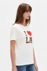 Remera blanca de manga corta y cuello redondo, con corte holgado y estampado frontal que dice 'I <3 LA' con letras de animal print y un corazón rojo.