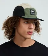 Gorra tipo 5 panel confeccionada en microfibra de poliamida, con diseño de bloques de colores en beige, negro y verde oliva. Presenta visera recta, cierre posterior ajustable y etiqueta frontal con gráfico y frase Stay Grounded.