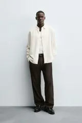 Camisa de corte regular fit confeccionada en tejido de algodón con textura de cuadrillé. Presenta cuello solapa, manga larga con puños abotonados y cierre frontal mediante botonadura.