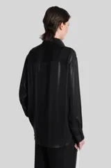 Camisa de mujer Diesel modelo C-Simplier, de manga larga y cierre frontal con botones, confeccionada en poliéster técnico con acabado brillante efecto cuero. Cuenta con bajo trasero alargado y logo Oval D bordado en el pecho.