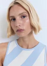 Vestido corto de punto fino, sin mangas, con cuello redondo y tirantes anchos, con diseño recto y estampado de rayas diagonales celestes y blancas.