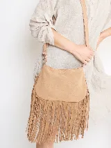 Bandolera de gamuza color beige con flecos largos en la parte inferior. Tiene correa larga regulable y herrajes plateados.