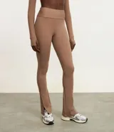 Pantalón deportivo tipo legging flare, color marrón topo, de tiro alto y con abertura lateral en el tobillo.