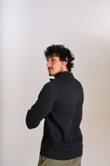 Buzo de cuello alto con cierre frontal parcial, manga larga y puños acanalados. Presenta un diseño liso en color negro con el logo de la marca bordado en el pecho.