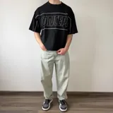 Remera gris oscuro de corte boxy y mangas cortas, con un gran estampado frontal en el pecho que dice "CONCEPT" en líneas blancas.