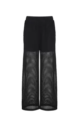 Pantalón calado negro de Le Lis Blanc, con tejido de punto transparente, corte ancho y cintura asimétrica con superposición frontal.