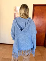 Saco tejido de punto color lavanda con diseño oversize, capucha integrada y detalle de flecos en el ruedo. Presenta mangas amplias y caída relajada.