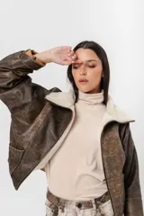 Chaqueta estilo bomber vintage de cuero marrón con cuello y solapa de corderito color crema. Cierre frontal con cremallera y bolsillos laterales.