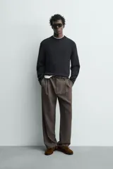 Pantalón straight fit color negro confeccionado en tejido con lana, con detalle de pliegues en el delantero, bolsillos frontales y traseros, y cierre frontal con cremallera y botón.
