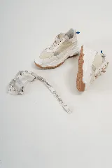 Championes chunky estilo tennis sneakers, color blanco y beige, con detalles en cuero y descarne. Incorporan un arnés desmontable con brillos y tachas, y suela de goma marrón.