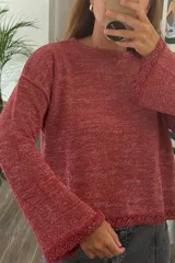 Sweater tejido de punto en color rojo con destellos de lurex. Presenta cuello redondo, mangas largas con terminación acampanada y detalle de borde festoneado en puños y ruedo.