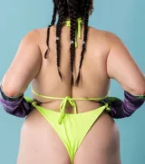 Bikini de lycra color verde flúor, compuesto por un corpiño triangular con tiras finas y una bombacha colaless con tiras laterales ajustables.