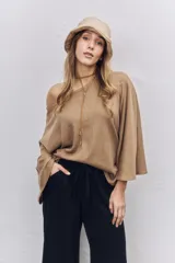 Buzo de punto color tostado con diseño de hombros caídos, cuello amplio y mangas anchas tipo murciélago.