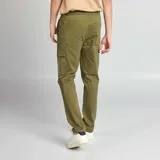 Pantalón tipo cargo color verde militar, con bolsillos laterales con solapa, corte ajustado y puños elásticos en los tobillos.