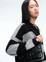 Sweater de tejido de punto con diseño a rayas horizontales en negro y gris. Presenta cuello en V con terminaciones desflecadas, corte holgado y mangas largas con puños desflecados.