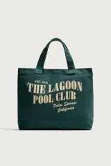 Bolso tipo shopper verde oscuro de tejido de algodón, con doble asa de mano y estampado frontal en color beige con la inscripción "The Lagoon Pool Club Palm Springs California".