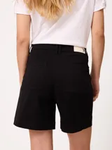 Short negro de gabardina con pinzas delanteras, bolsillos laterales y cierre frontal con botón metálico.