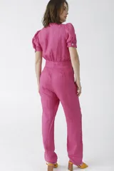 Mono negro de lino con escote pronunciado en V y nudo frontal que deja ver un corte en la cintura. Mangas cortas abullonadas y pantalón de corte recto.