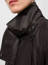Gabardina larga color marrón con acabado efecto encerado, cuello con solapas anchas, cierre cruzado y bolsillos laterales. Incluye cinturón ajustable y detalles de trabillas en los puños.