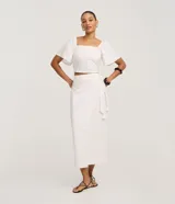 Pollera recta midi color blanco, confeccionada en tejido laise con bordados geométricos. Cuenta con diseño cruzado tipo pareo (traspase) y lazo ajustable en la cintura.