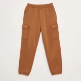Pantalón de chándal color tostado, con cintura elástica, bolsillos laterales tipo cargo con solapa y puños elásticos en los tobillos.