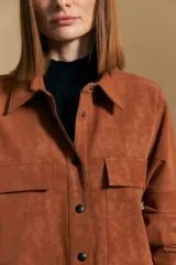 Sobrecamisa de efecto engomado en color negro, con textura lavada, cuello clásico, cierre frontal con botones a tono y bolsillos frontales con solapa.