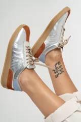 Zapatillas deportivas de cuero color beige con detalles en naranja y suela marrón.