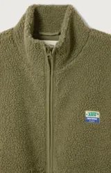 Campera de corderito con efecto shearling, color verde oliva, de corte holgado, cuello alto y cierre frontal completo. Presenta un pequeño parche con logo en el pecho.