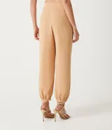 Pantalón zanahoria color beige de crepé con cinturilla ancha, botones con forma de león y pinzas delanteras.