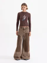 Pantalon de jean de corte wide leg en color marrón, con diseño de parches en tonos contrastantes y estilo carpintero. Presenta bolsillos diagonales frontales y bolsillos plaque en la parte posterior.