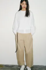 Camiseta oversize de cuello redondo y manga larga con puños abotonados. Confeccionada en algodón, presenta un diseño con combinación de tejidos a tono y bajo asimétrico.