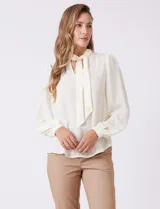 Blusa de gasa color crema, marca Zac & Rachel, con escote en V y lazo para anudar en el cuello. Mangas largas con puños abotonados.