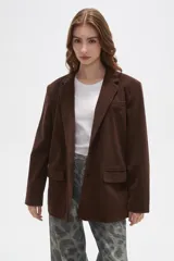 Blazer de pana color marrón, con corte holgado, cuello solapa y cierre frontal con dos botones. Presenta bolsillos laterales con solapa y un bolsillo superior en el pecho.