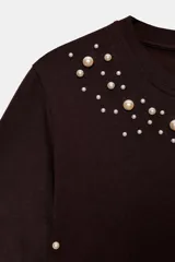 Camiseta de manga corta y cuello redondo, color marrón oscuro, con apliques de perlas de diferentes tamaños distribuidos en el escote y el bajo.
