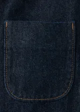 Chaqueta corta de denim en color azul oscuro, con cuello clásico, cierre frontal con botones, mangas largas y un bolsillo aplicado en el pecho.