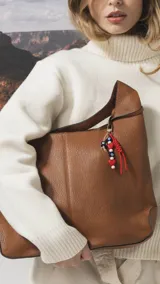 Cartera tipo hobo de cuero sintético color tostado, con diseño de hombro, costuras verticales decorativas y monedero pequeño extraíble a tono.