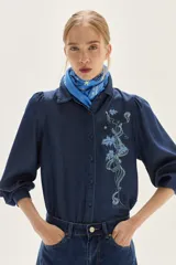 Camisa de lyocell azul oscuro con bordado floral a tono en el pecho y mangas voluminosas. Presenta un calce recto.