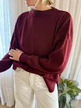 Sweater de punto acanalado color bordó, con cuello redondo, mangas largas con puños ajustados y diseño holgado con tajos laterales en el ruedo.