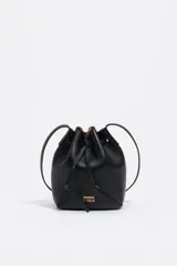 Bolso tipo saco de tamaño pequeño confeccionado en piel vacuna negra, con cierre de cordón ajustable, asa larga regulable y logo de la marca en letras metálicas doradas en la parte frontal.