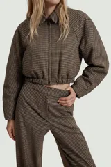Cazadora estilo bomber acolchada con estampado de pata de gallo, cuello subido con trabilla y botón, manga larga y cierre frontal con cremallera. Presenta bolsillos delanteros y bajo elástico.