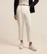 Pantalón carrot negro de sastrería, con bolsillos, pliegues y cinturón fino de cuero sintético.
