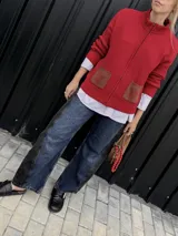 Campera tejida con textura vanizada a rayas horizontales en blanco y negro, con cierre frontal y flecos negros en forma de V en el pecho.