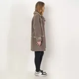 Tapado de textura tipo corderito en color taupe, con diseño de corte recto y largo. Presenta detalles de paneles lisos en los laterales y en las mangas, cuello con solapas y cierre frontal.