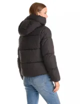 Campera puffer de corte recto y acabado mate, con diseño de bloques horizontales acolchados. Presenta capucha integrada con cordones de ajuste, cierre frontal metálico y bolsillos laterales invisibles. Incluye puños elásticos internos para mayor protección contra el frío.