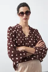 Camisa de manga larga color marrón con estampado de lunares blancos, cuello mao y cierre frontal con botones.