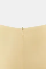 Vestido corto color amarillo claro, con cuello barco, mangas cortas abullonadas y pliegues en la parte delantera. Presenta falsos bolsillos de vivo y costuras marcadas. Cierre en la espalda con cremallera oculta.