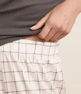 Pijama largo con blusa gris acanalada de cuello redondo y pantalón largo con estampado de cuadros y cintura elástica.