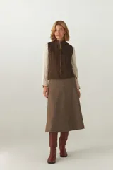 Chaleco corto y entallado de lana fina sin teñir, color marrón claro con textura de espiga sutil. Presenta cierre frontal y detalles de alforzas verticales en el frente y la espalda.